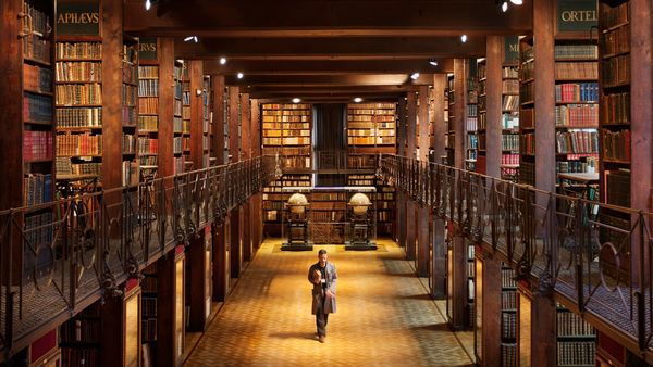 Een man wandelt door de statige bibliotheek in de Nottebohmzaal.