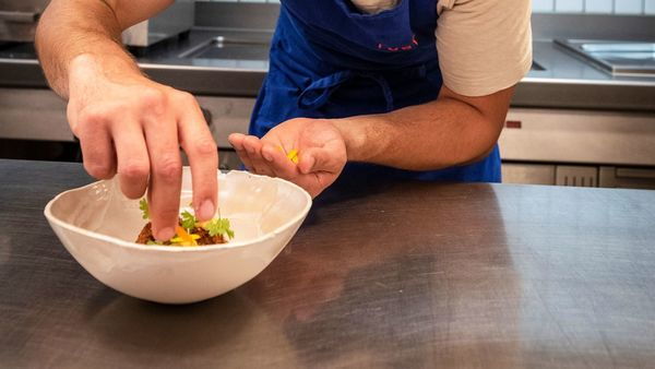 Een kok dresseert een gerecht op een bord in de keuken van het restaurant