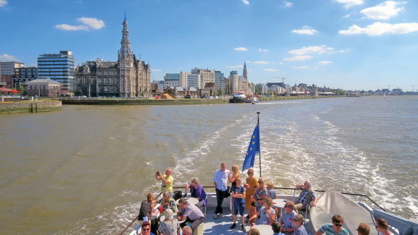 Groep mensen op boot met Antwerpse skyline op de achtergrond