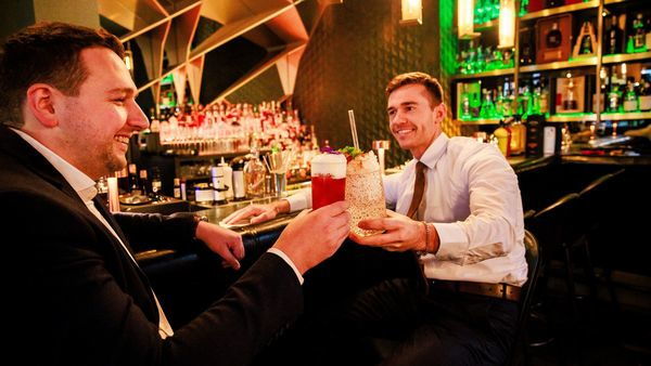 Twee mannen klinken met een cocktail in de hand 