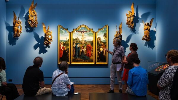 Quelques personnes regardent un triptyque de Quinten Massijs dans une salle du musée.