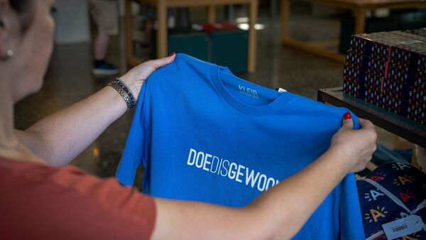 Frau hält T-Shirt von Kleir mit dem Spruch 'Doedisgewoon' in der Hand