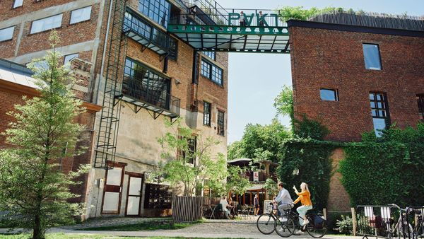 A man and a woman cycle past buildings decorated as coffee bars and rooftop farms.