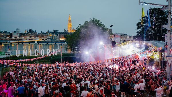 Unicorn Festival: mensen staan te dansen bij avondval met uitzicht op de kathedraal van Antwerpen.