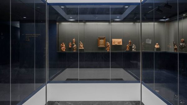 Une salle de musée moderne et rénovée avec beaucoup de verre et quelques œuvres d'art sur le mur.