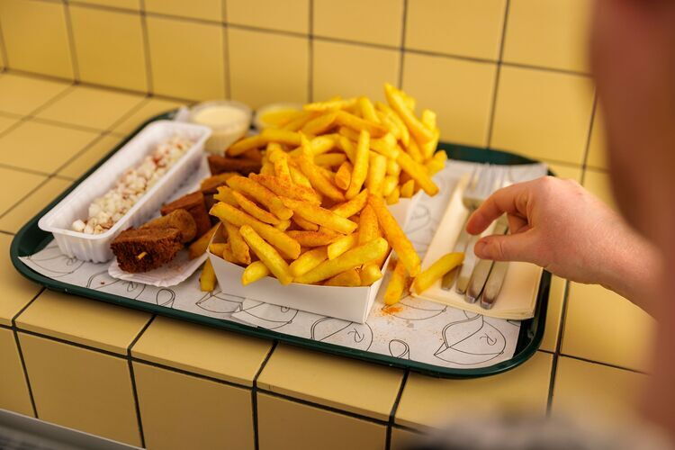 Maaltijd met frieten, snacks en saus op een dienblad.