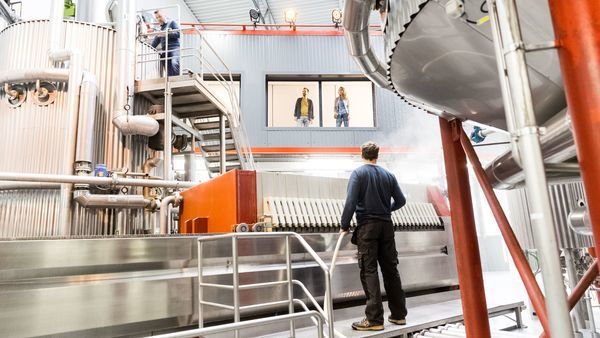 People are at work in a brewery, others watch.