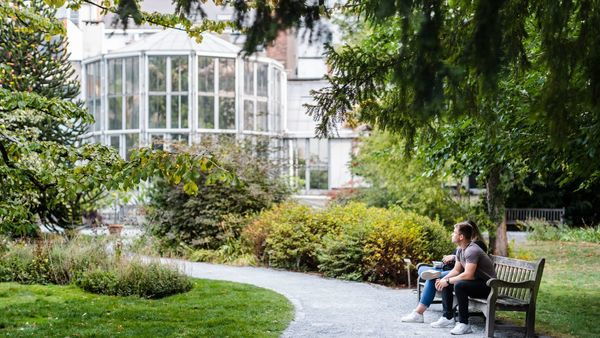 Twee mensen op een bank genieten van de plantentuin.