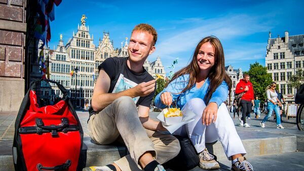 Un homm et une femme mangent des frites sur les marches de l'hôtel de ville.