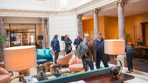 Un grupo de personas se encuentra en el majestuoso y elegante vestíbulo del Hotel Franq.