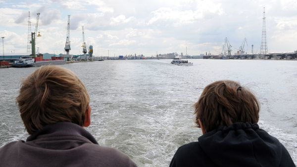 Two passengers on the deck of a ship watching the Scheldt.