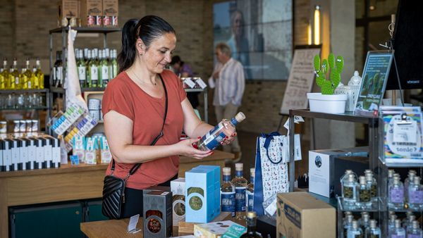 Frau betrachtet eine Flasche Elixir d'Anvers an einer Theke