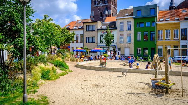 Terrace with colourful parasols and a playground in the foreground