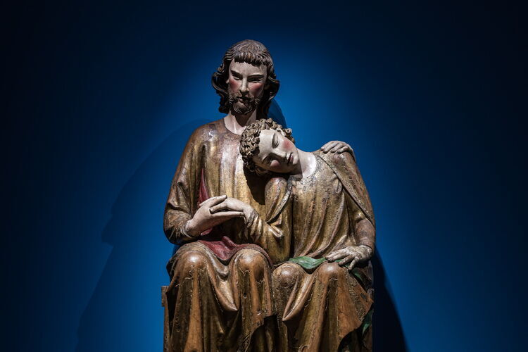 Eine große Holzskulptur von Christus und Johannes, der seinen Kopf auf Jesu Schulter ruht.