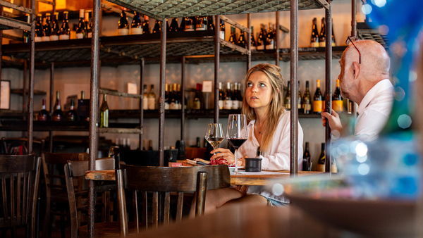 Vrouw zit aan tafel met glas wijn