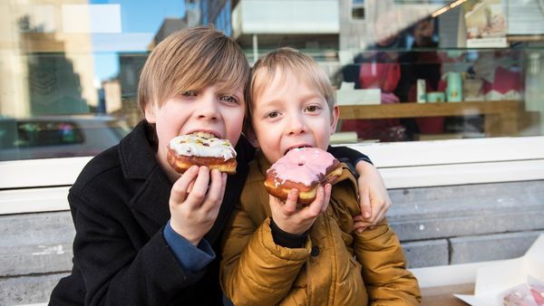 Twee kleine jongens genieten arm in arm van een donut