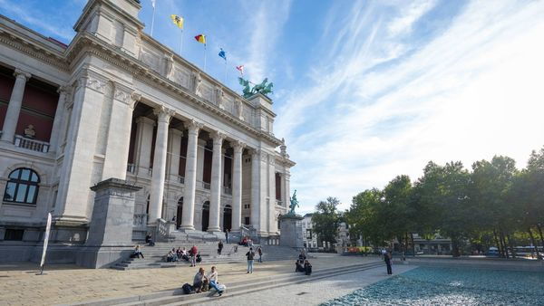 Des dizaines de personnes sont assises et debout sur les marches et le bassin devant les majestueuses colonnes du Musée royal des Beaux-Arts d'Anvers.