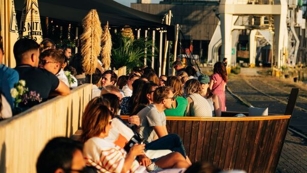 Menschen genießen Sonne, Getränke und gute Gesellschaft auf der Terrasse von Gazon Antwerp