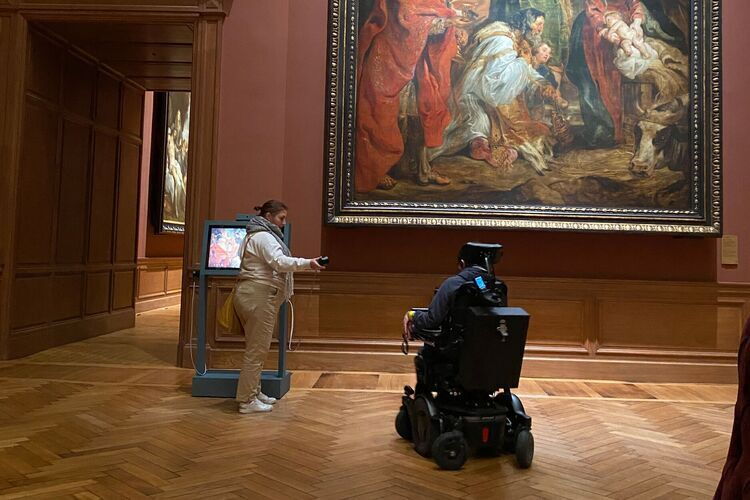 Simon en zijn begeleider luisteren naar een audio-fragment in een museumzaal.