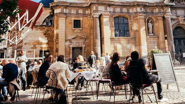 Terras met mensen aan een plein van een kerk