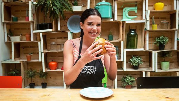 Een restaurantmedewerkster lacht terwijl ze een vegetarische hamburger vasthoudt