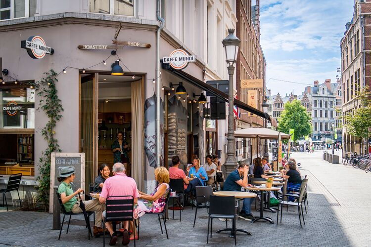 Mehrere Personen sitzen auf einer Terrasse vor der Kaffeebar Caffe Mundi.