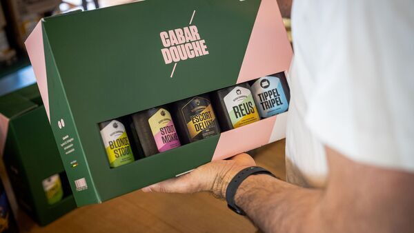 Jemand hält ein Geschenkpaket der Biermarke Cabardouche
