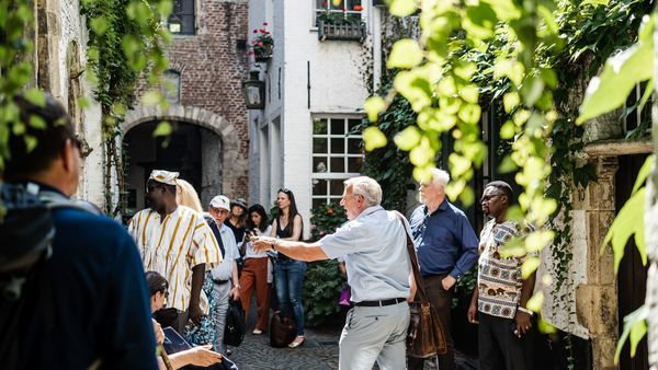 Enthusiastic city guide talks to tourists in the Vlaeykensgang