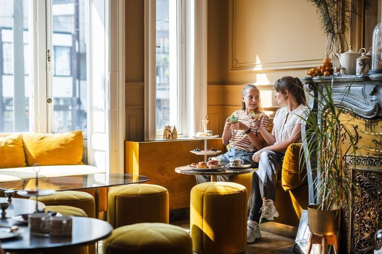 Moeder en dochter genieten in een verlichte ruimte in zeteltjes van high tea.
