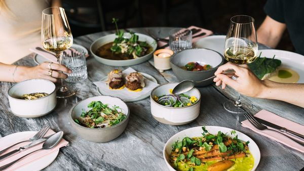 Handen van mensen bedienen zich met gerechten en glazen wijn op een tafel