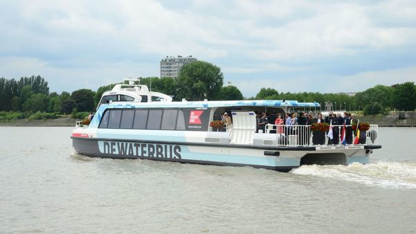 A boat with part of its deck covered transports a group of people across a river