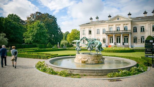 Wandelaars lopen voorbij Kasteel Den Brandt op een zonnige dag.