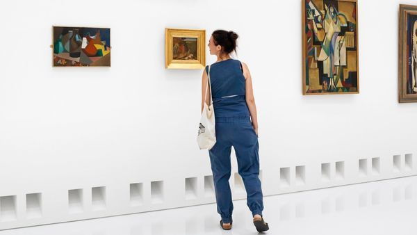 Une femme regarde de l'art moderne dans une salle de musée blanche.