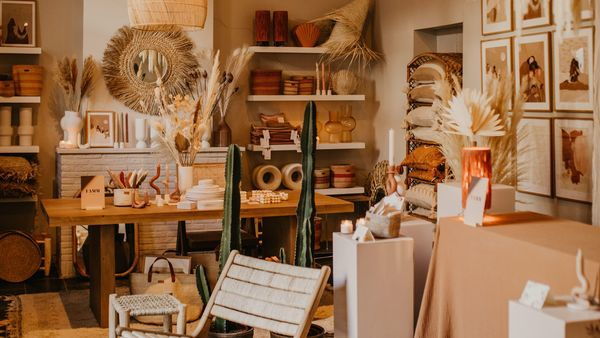 Een spiegel, vazen, droogbloemen en fotokaders in beige tinten staan geëtaleerd in een interieurwinkel