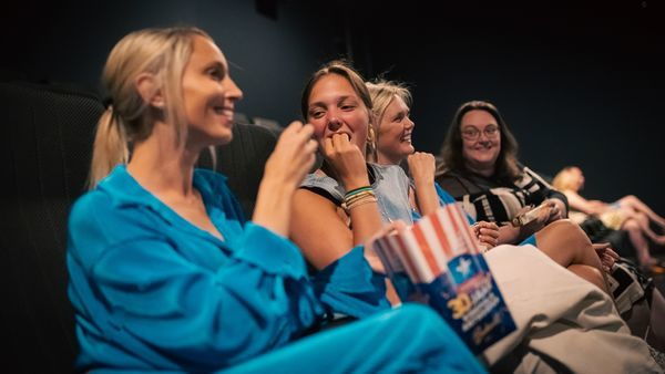 Cheerful ladies enjoy popcorn and film at the cinema