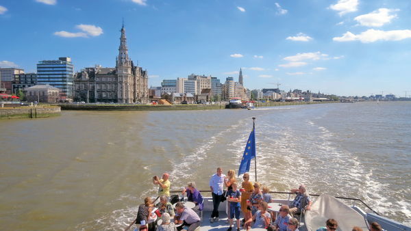 Gruppe von Menschen auf einem Boot mit der Skyline von Antwerpen im Hintergrund