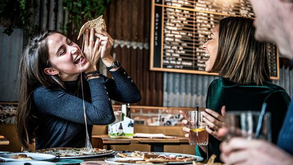 Vriendinnen smullen van pizza bij Otomat