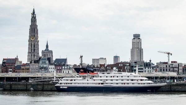 A cruise ship sails on the Scheldt past the cathedral and the Boerentoren skyscraper.