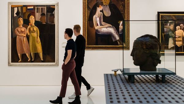Deux hommes passent devant des tableaux de maîtres modernes dans une salle blanche.