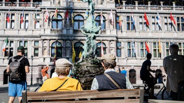 Two gentlemen on a bench in the Grote Markt stare at Brabo and City Hall.
