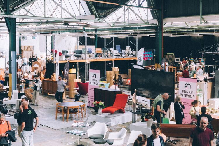 A Design Market in de Blikfabriek. Je ziet allemaal standjes met zowel meubels als kunst als grafische ontwerp.