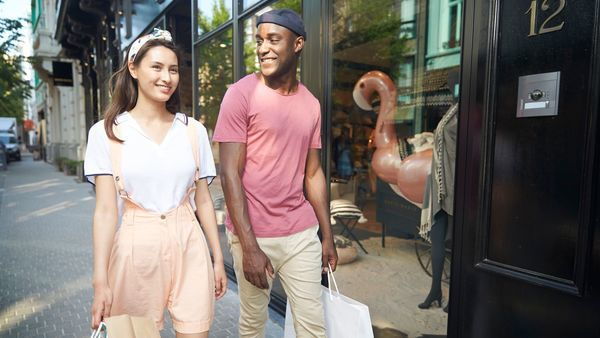Couple with shopping bags walks past window of Marie Marie