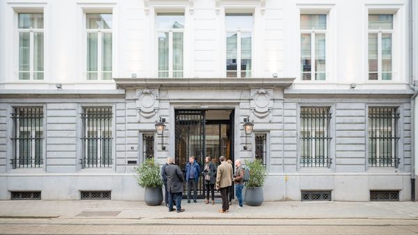 Een groep mensen aan de voorgevel van een hotel