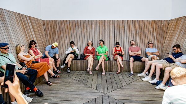 Visiteurs profitant du beau temps sur la terrasse du M HKA sur un banc en bois.