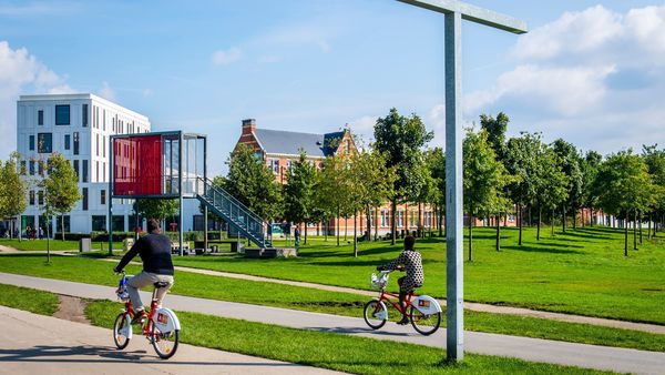 Two people cycle the Velo through Park Spoor Noord