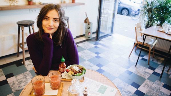Chica en una mesa con comida y bebida en un bar 