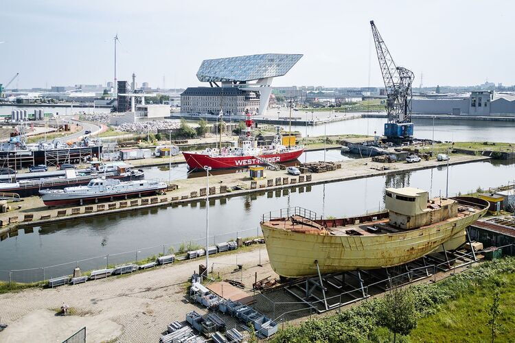 Dry dock site, shipyard in the Port of Antwerp with historic boats and the Port House in the background.
