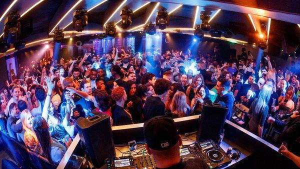 Un guitarrista toca su instrumento en medio del público en una discoteca con luces de discoteca