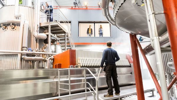 Menschen arbeiten in einer Brauerei, andere Menschen schauen zu.