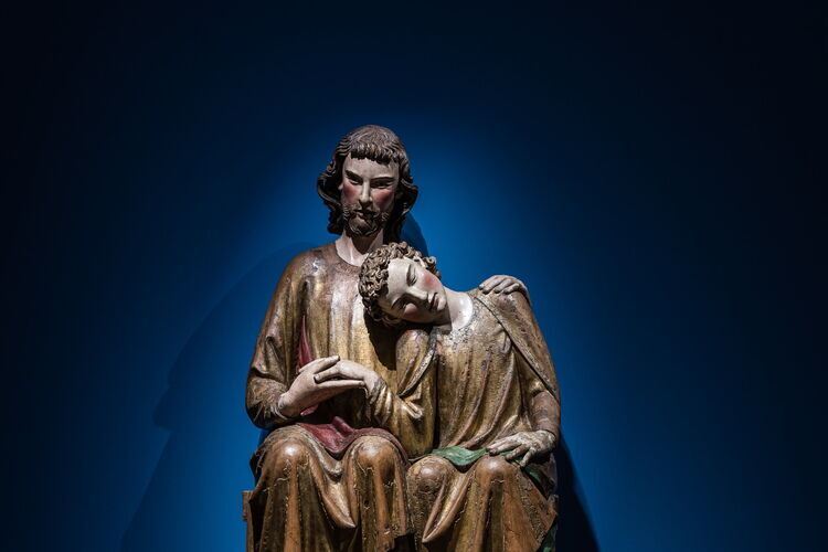 A large wooden sculpture of Christ and John, who rests his head on Jesus' shoulder.